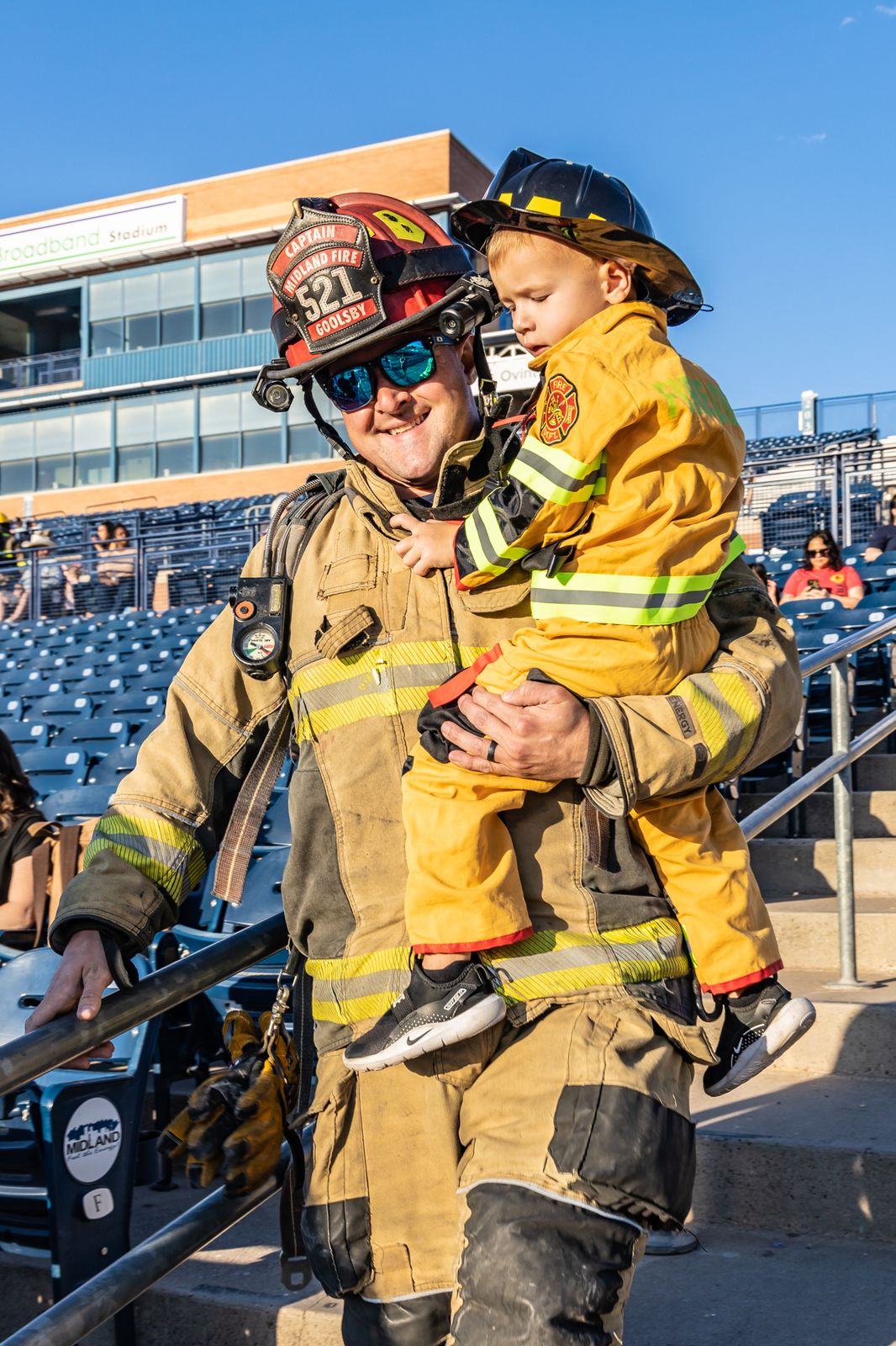 Firefighter carrying a child in turnout gear up the stairs